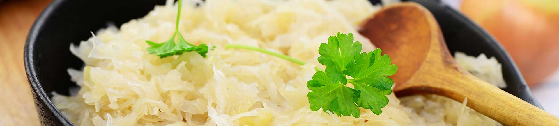 Choucroute cuite dans une casserole noire avec une cuillère en bois ; décoré avec du persil